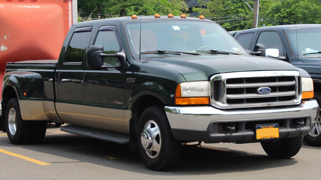 Green and tan 2000 Ford F-350 Super Duty dually with a 7.3L Power Stroke and trailer