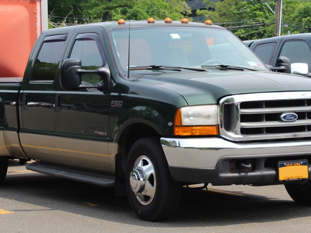 Green and tan 2000 Ford F-350 Super Duty dually with a 7.3L Power Stroke and trailer